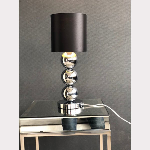 Kleine chroom bollamp tafelmodel met verlichting aan op een tafel